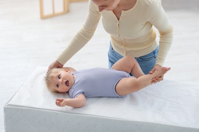 Photo of Mother with her cute baby on changing table at home