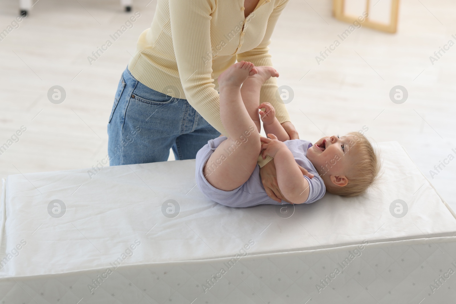 Mother playing with her cute baby on changing table at home, closeup Photo of Mother playing with her cute baby on changing table at home, closeup