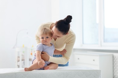 Photo of Mother with her cute baby on changing table at home