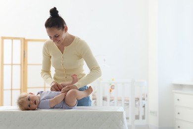 Photo of Mother playing with her cute baby on changing table at home, space for text