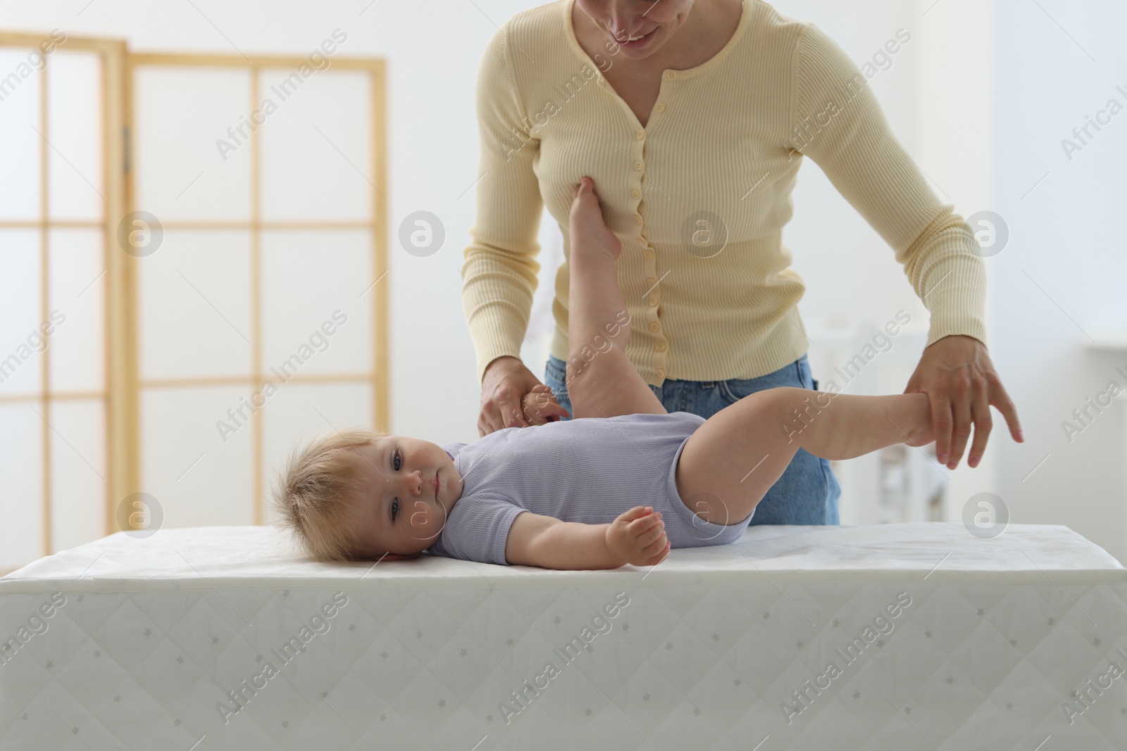 Mother playing with her cute baby on changing table at home, closeup Photo of Mother playing with her cute baby on changing table at home, closeup