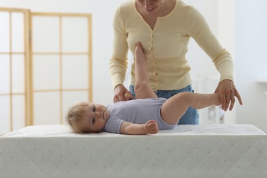 Photo of Mother playing with her cute baby on changing table at home, closeup
