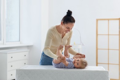 Photo of Mother playing with her cute baby on changing table at home