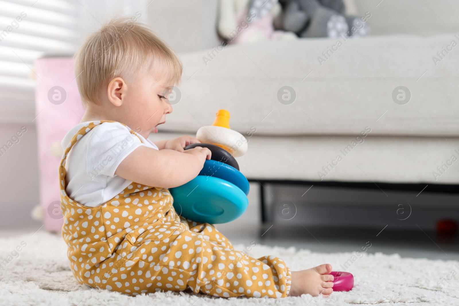 Cute little baby playing with toy pyramid on floor at home, space for text Photo of Cute little baby playing with toy pyramid on floor at home, space for text