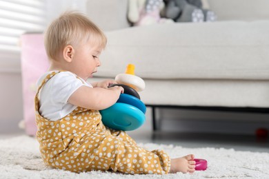 Photo of Cute little baby playing with toy pyramid on floor at home, space for text