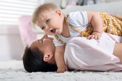 Photo of Mother and her little baby on floor at home
