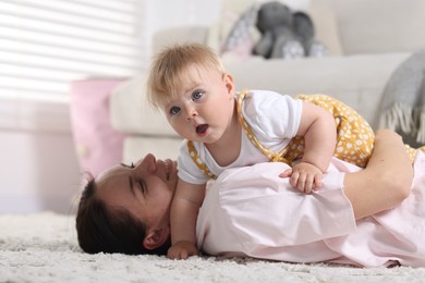Photo of Mother and her little baby on floor at home