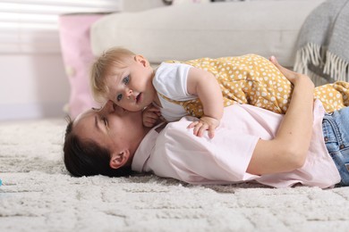 Photo of Mother and her little baby on floor at home