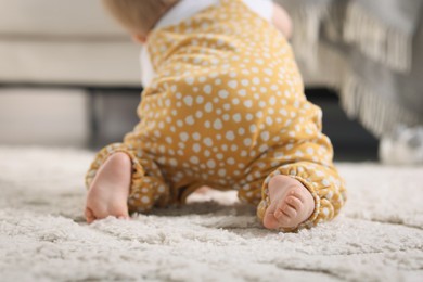 Photo of Cute little baby crawling on floor at home, closeup