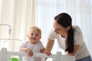 Photo of Mother playing with her cute baby in crib at home