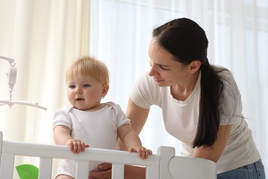 Photo of Mother playing with her cute baby in crib at home