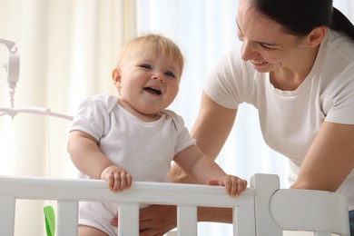 Photo of Mother playing with her cute baby in crib at home