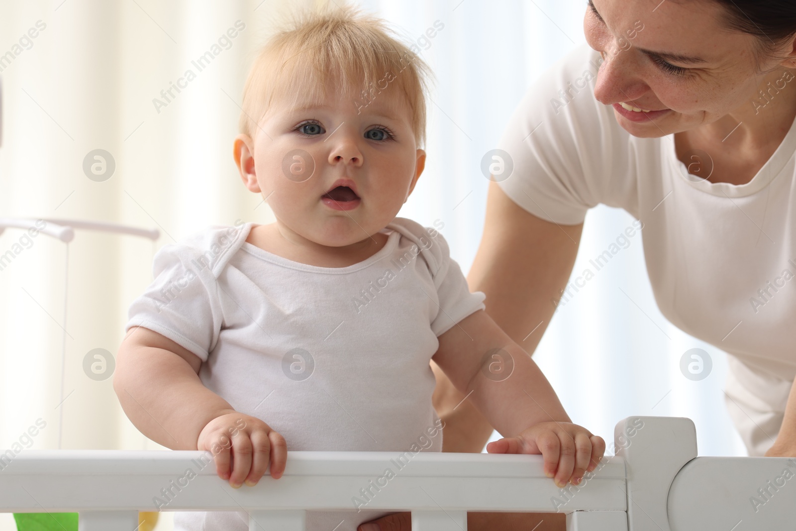 Mother playing with her cute baby in crib at home Photo of Mother playing with her cute baby in crib at home