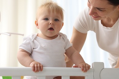 Photo of Mother playing with her cute baby in crib at home