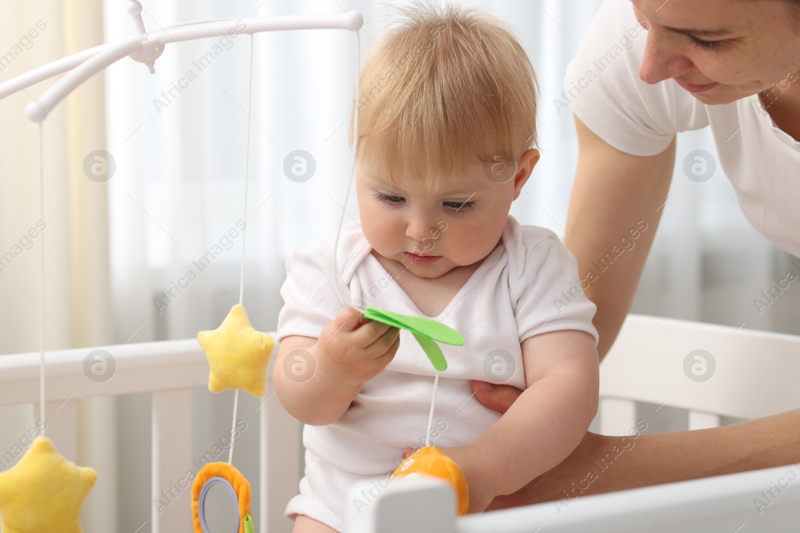 Mother playing with her cute baby in crib at home, closeup Photo of Mother playing with her cute baby in crib at home, closeup