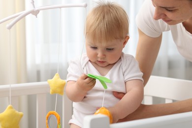 Photo of Mother playing with her cute baby in crib at home, closeup