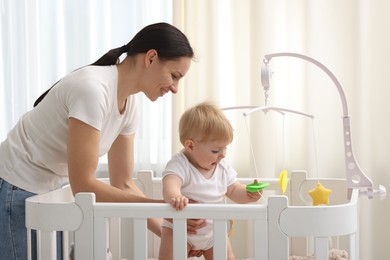 Photo of Mother playing with her cute baby in crib at home