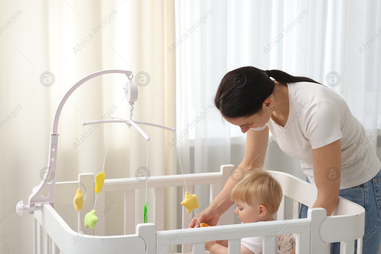 Mother playing with her cute baby in crib at home Photo of Mother playing with her cute baby in crib at home
