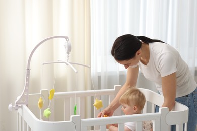 Photo of Mother playing with her cute baby in crib at home