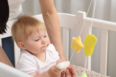 Photo of Mother playing with her cute baby in crib at home, closeup