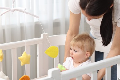 Photo of Mother playing with her cute baby in crib at home