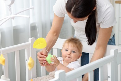 Photo of Mother playing with her cute baby in crib at home