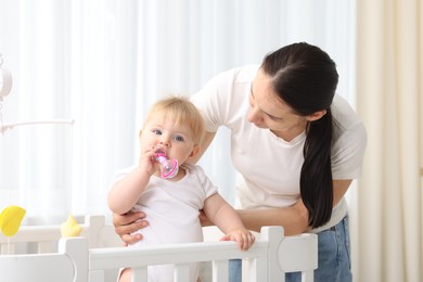 Photo of Mother playing with her cute baby in crib at home