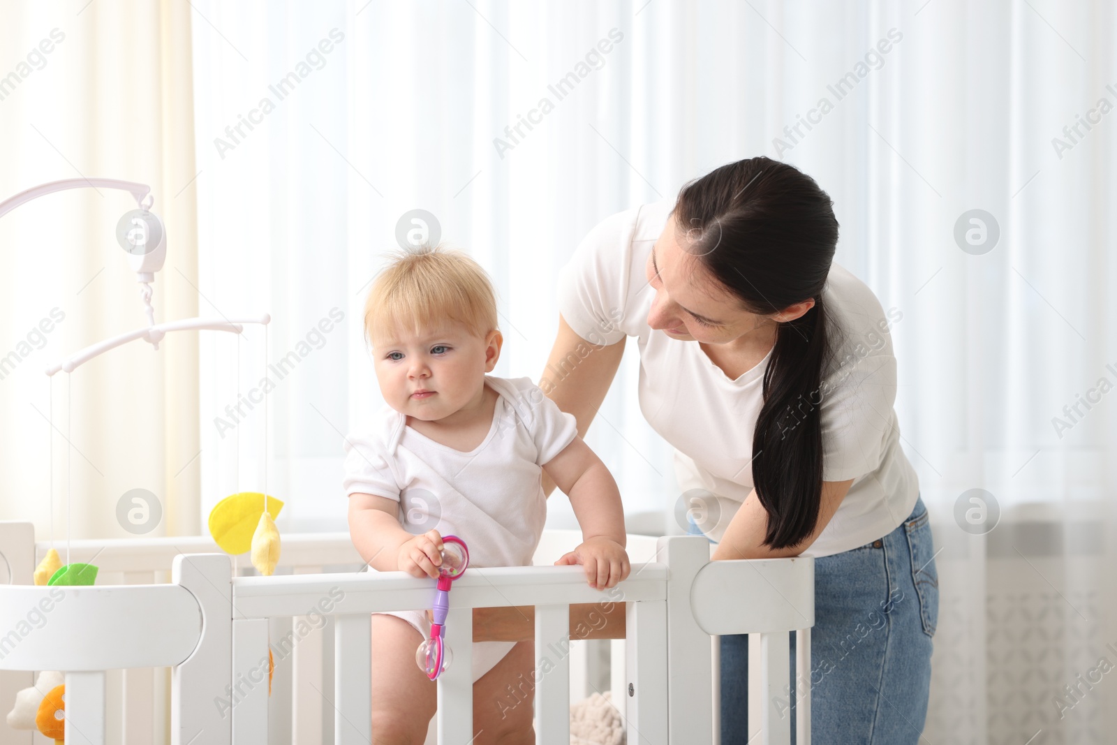 Mother playing with her cute baby in crib at home Photo of Mother playing with her cute baby in crib at home