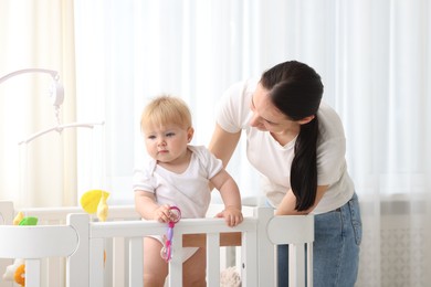 Photo of Mother playing with her cute baby in crib at home