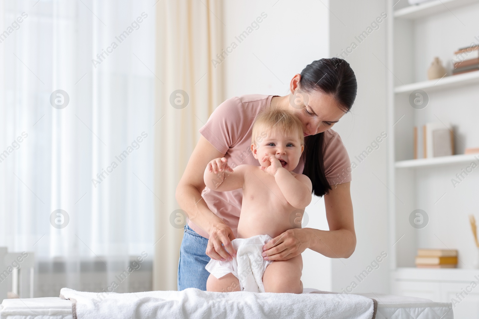 Mother changing her baby's diaper on table at home Photo of Mother changing her baby's diaper on table at home