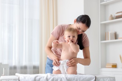 Photo of Mother changing her baby's diaper on table at home