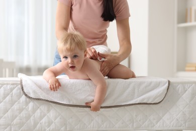 Photo of Mother changing her baby's diaper on table at home, closeup