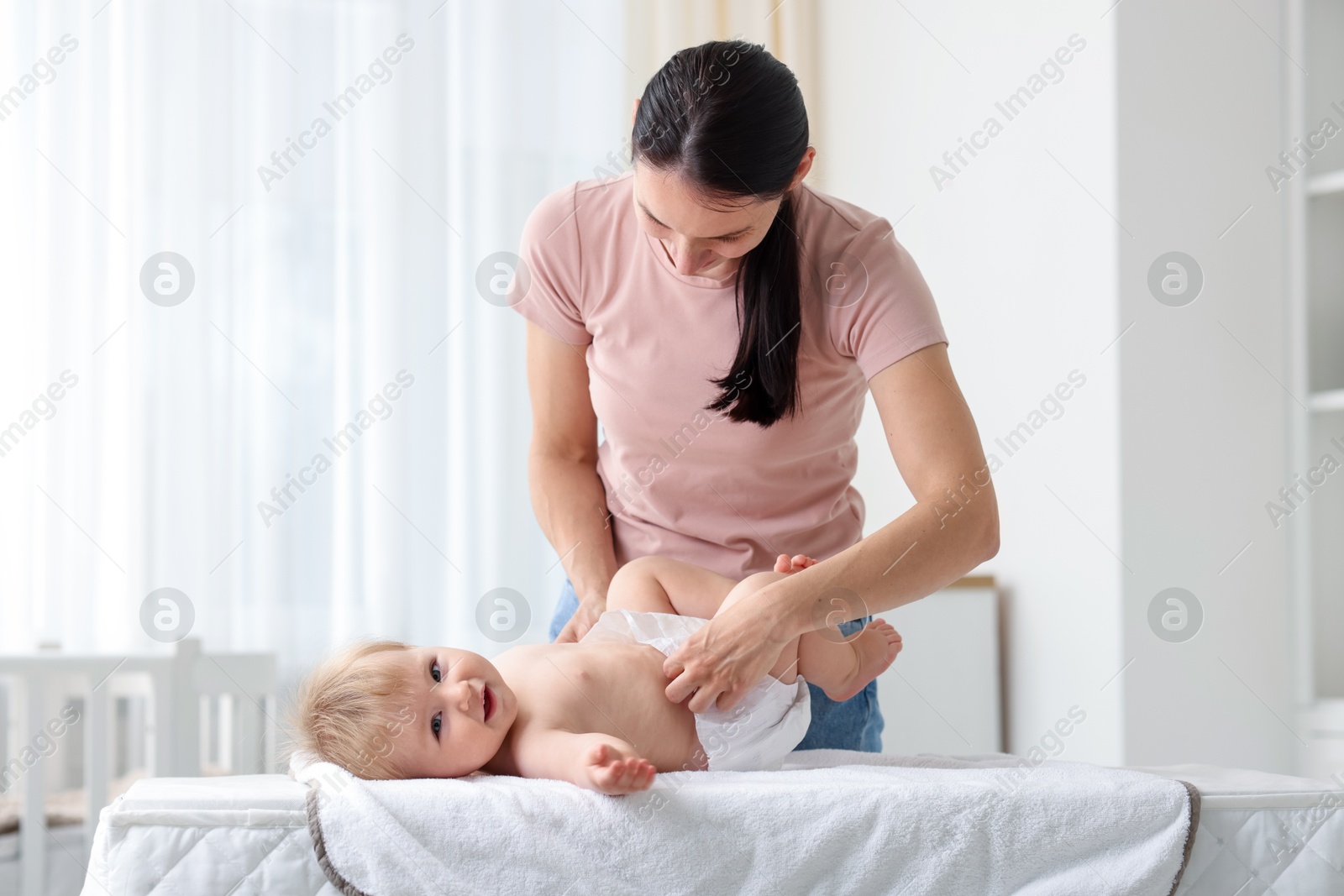 Mother changing her baby's diaper on table at home Photo of Mother changing her baby's diaper on table at home