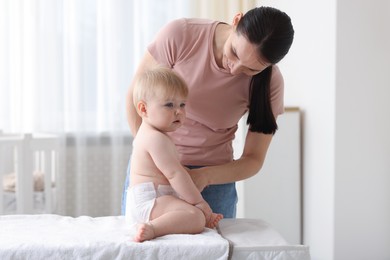 Photo of Mother changing her baby's diaper on table at home