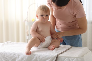 Photo of Mother changing her baby's diaper on table at home