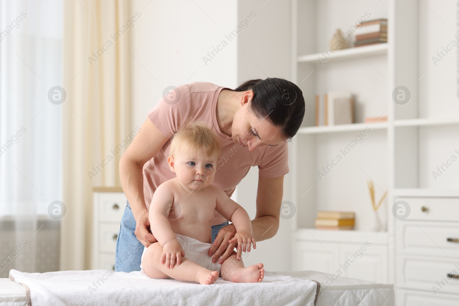 Mother changing her baby's diaper on table at home Photo of Mother changing her baby's diaper on table at home