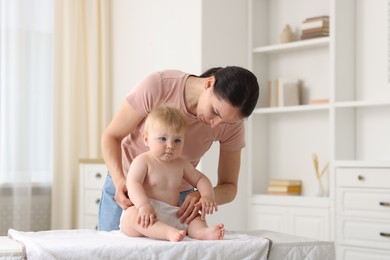 Photo of Mother changing her baby's diaper on table at home