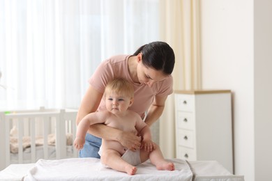 Photo of Mother changing her baby's diaper on table at home