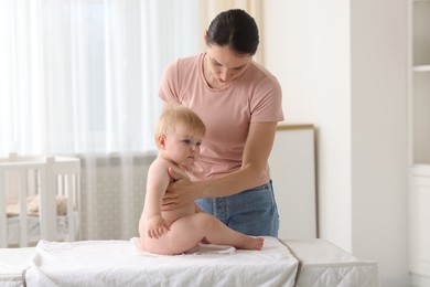 Photo of Mother changing her baby's diaper on table at home