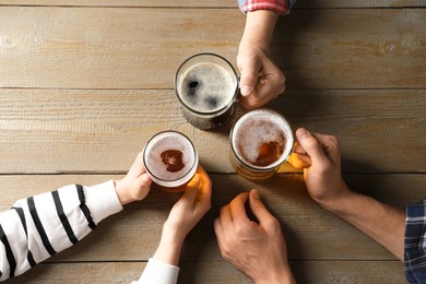 Photo of Friends with glasses of beer at wooden table, top view