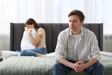 Photo of Woman and man having quarrel on bed at home, selective focus