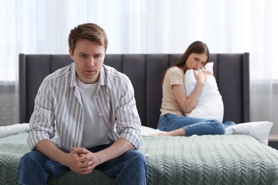 Photo of Woman and man having quarrel on bed at home, selective focus