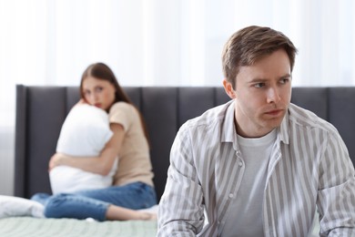 Photo of Woman and man having quarrel on bed at home, selective focus