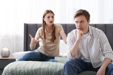 Photo of Woman and man having quarrel on bed at home