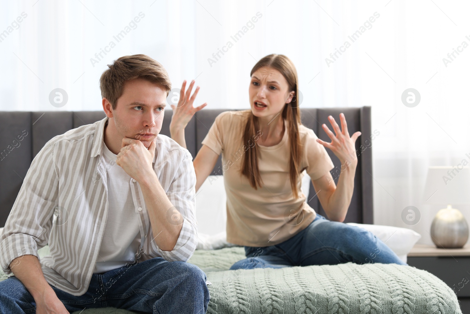 Photo of Woman and man having quarrel on bed at home