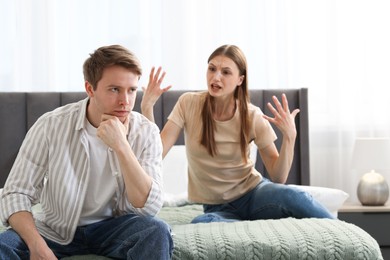 Photo of Woman and man having quarrel on bed at home