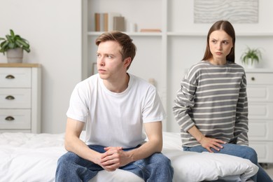 Photo of Woman and man having quarrel on bed at home