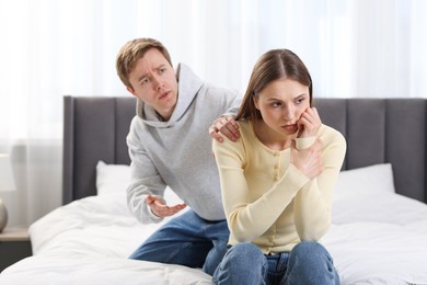 Photo of Woman and man having quarrel on bed at home