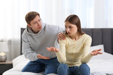 Photo of Woman and man having quarrel on bed at home