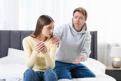 Photo of Woman and man having quarrel on bed at home